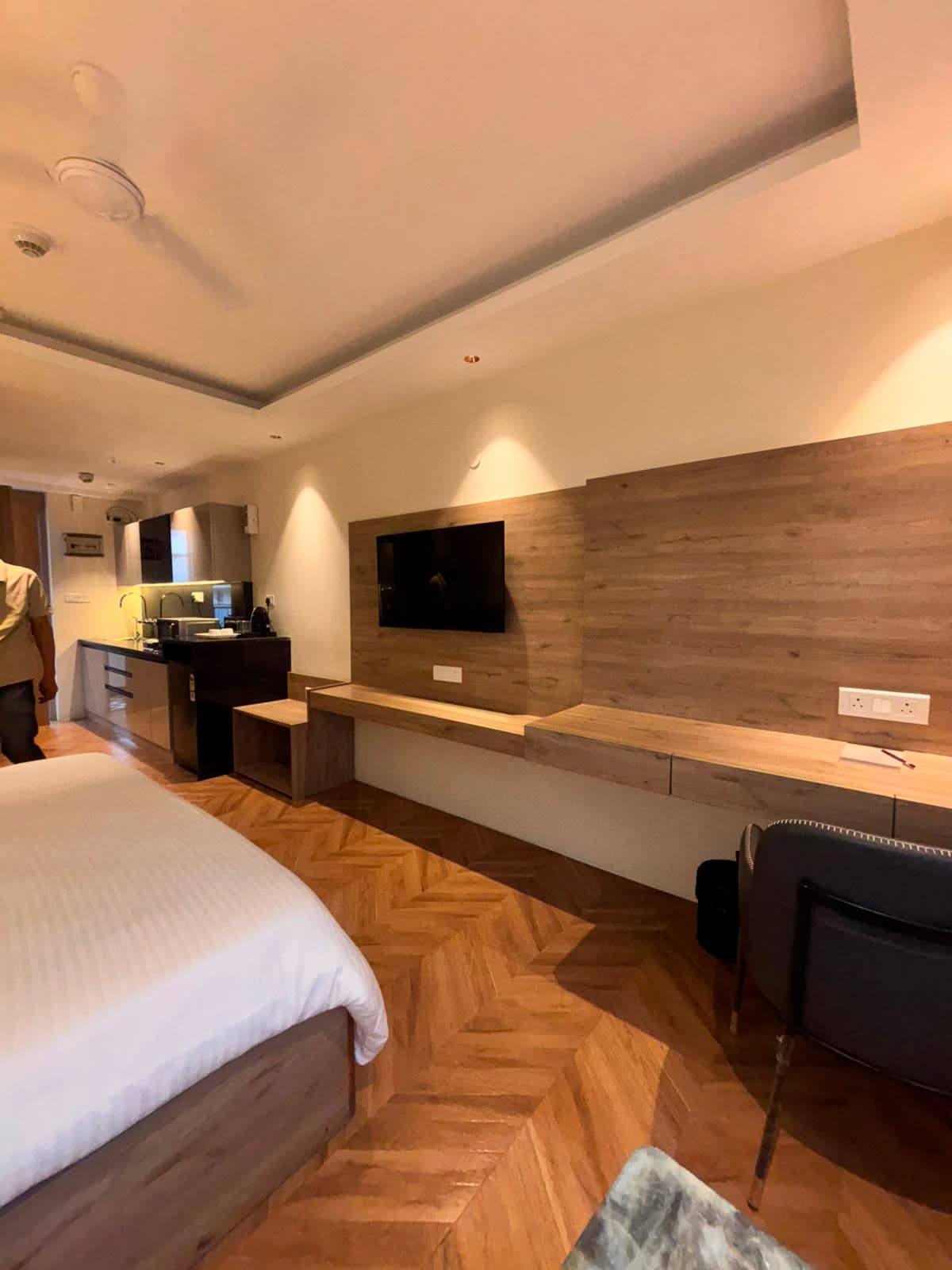 Wall-mounted TV above the dedicated workspace and herringbone wood flooring