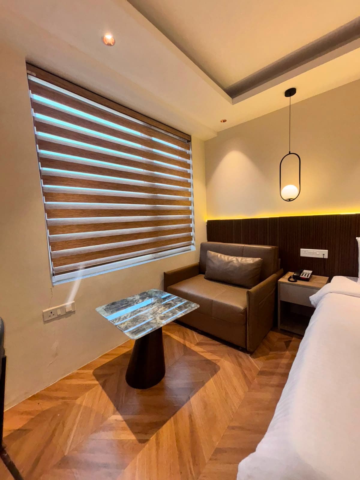 Seating corner with a compact sofa, marble side table and window blinds